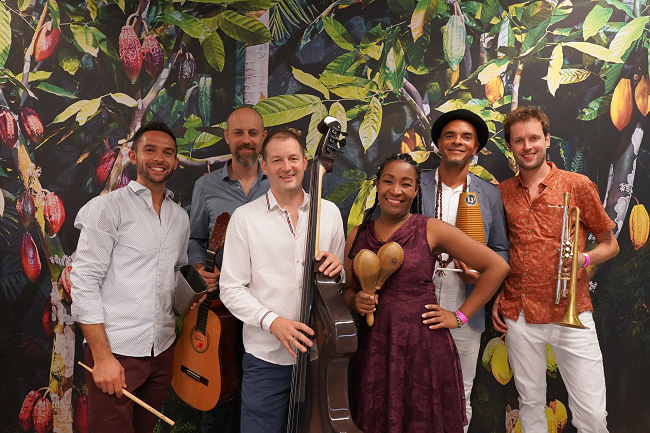 The six members of Arturo y Su Azucaribe together with a nature mural in the background