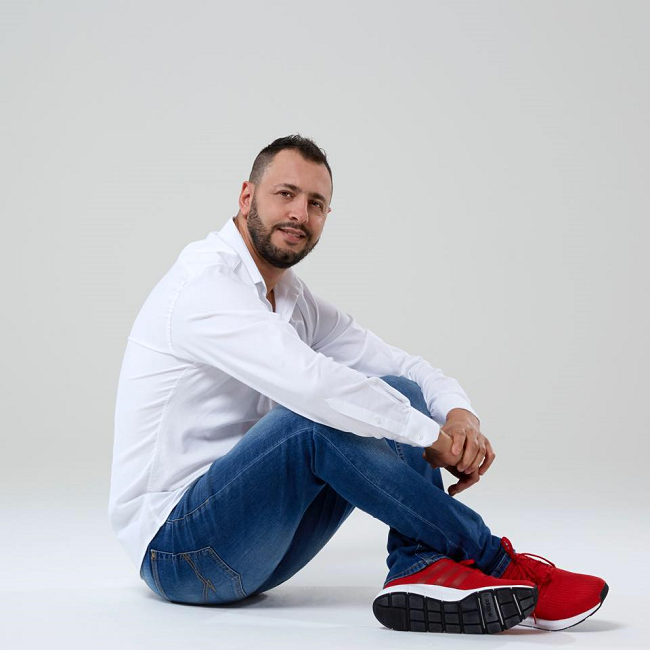 Fadi K dressed in jeans and a white shirt with red sports shoes