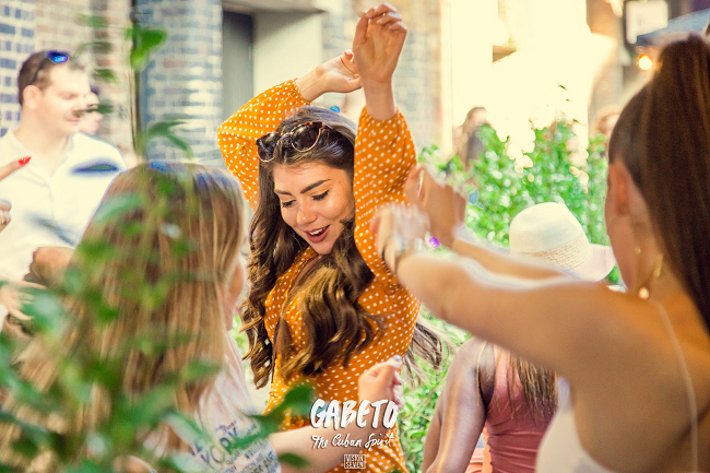 latin woman with orange dress dancing in gabeto restaurant / bar